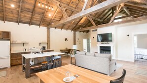 A spacious living area with a wooden ceiling, a dining table, a sofa, and a fireplace. - Pine Cove Treehouses & Cabins (Millersburg)