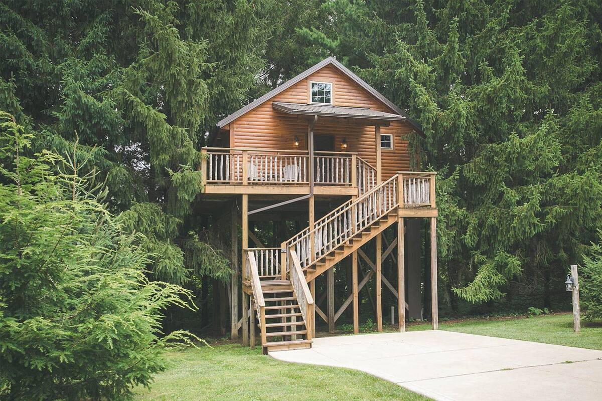 A wooden cabin with a balcony and a staircase leading to a deck.