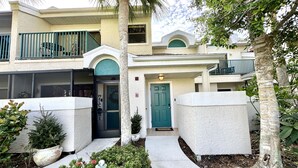 A two-story building with a welcoming entrance, a balcony, and a well-maintained garden. - Peaceful beach townhouse  (Naples)