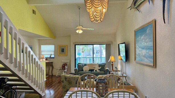 A spacious living area with a dining table, chairs, a sofa, and a staircase. - Peaceful beach townhouse  (Naples)
