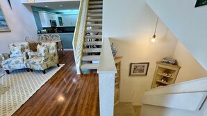 A staircase leading to a second floor, a dining area with floral-patterned chairs, and a kitchen in the background. - Peaceful beach townhouse  (Naples)