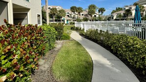 A residential area with a paved walkway, a white picket fence, and a row of townhouses with balconies. - Peaceful beach townhouse  (Naples)