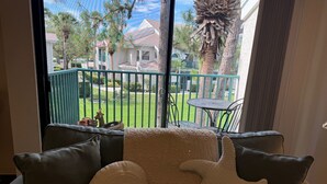 A view from a window to a balcony with a green railing, a small table, and a chair. - Peaceful beach townhouse  (Naples)