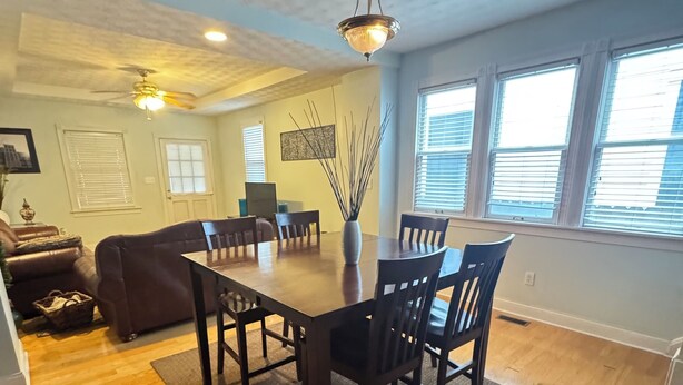 A dining area with a wooden table and chairs, a ceiling fan, and a vase with branches. - Minutes from downtown, the fairgrounds and the Speedway! Great Neighborhood! (Indianapolis)