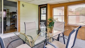 A glass-top table with four chairs, a vase, and a potted plant in a room with wooden walls and a door leading to another room. - Vintage Windsor Home: Private Yard & Covered Deck (Windsor)