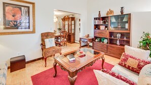 A living room with a wooden coffee table, a sofa, a patterned armchair, a wooden cabinet with glass doors, and a framed painting on the wall. - Vintage Windsor Home: Private Yard & Covered Deck (Windsor)