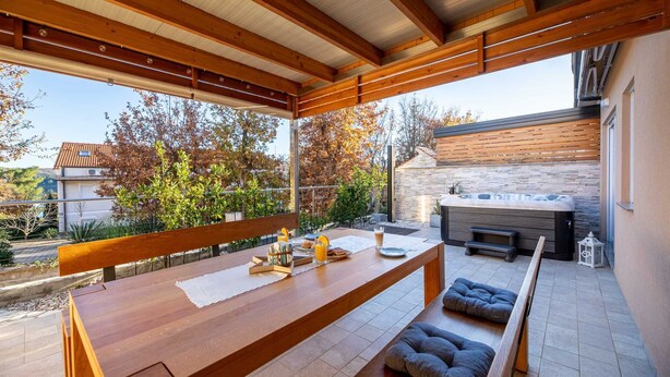 Eine Außenpatio mit Holztisch, Bänken und einem Whirlpool.
