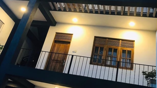 Un edificio di due piani con un balcone, diverse finestre e un tetto con rivestimento in metallo ondulato.