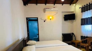 Una camera d'albergo con un letto, una sedia, una scrivania e una televisione.