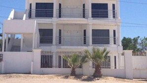 Un bâtiment à deux étages, doté d’un toit plat, de grandes fenêtres et d’une entrée fermée par un portail.