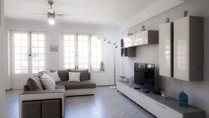 A modern living room with a sectional sofa, a flat-screen TV, and a minimalist design.