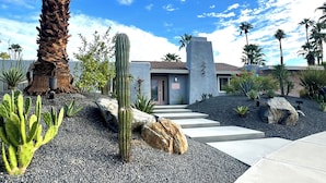 A modern building with a concrete facade, a large palm tree, and various cacti in the foreground. - 'Miles Away' A Desert Oasis - Palm Springs Style! (Palm Springs)
