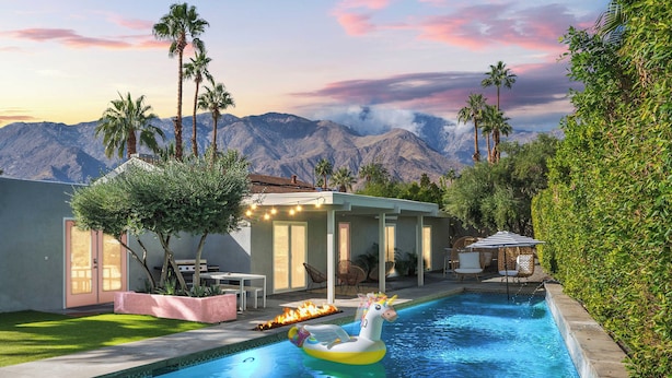 A swimming pool with a unicorn float, surrounded by palm trees and a mountain backdrop. - 'Miles Away' A Desert Oasis - Palm Springs Style! (Palm Springs)