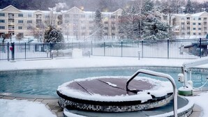 A snow-covered outdoor swimming pool with a mosaic deck, surrounded by a fence and buildings in the background. - Embark on Alpine Escapades: Bentley Brook Resort Unveils Ski-In/Ski-Out Bliss  (Hancock)