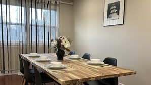 A dining area with a wooden table set for four, black chairs, and a vase with flowers.