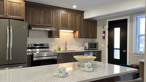 A modern kitchen with wooden cabinets, stainless steel appliances, and a granite countertop.