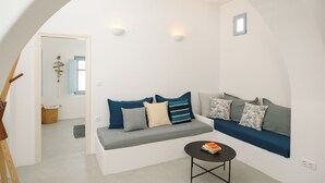 A modern living room with a white sofa, a small round table, and a view through an archway.