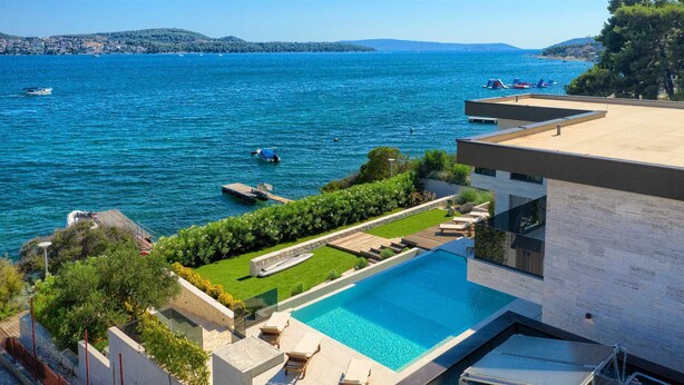 A modern villa with a private pool overlooking a lake.