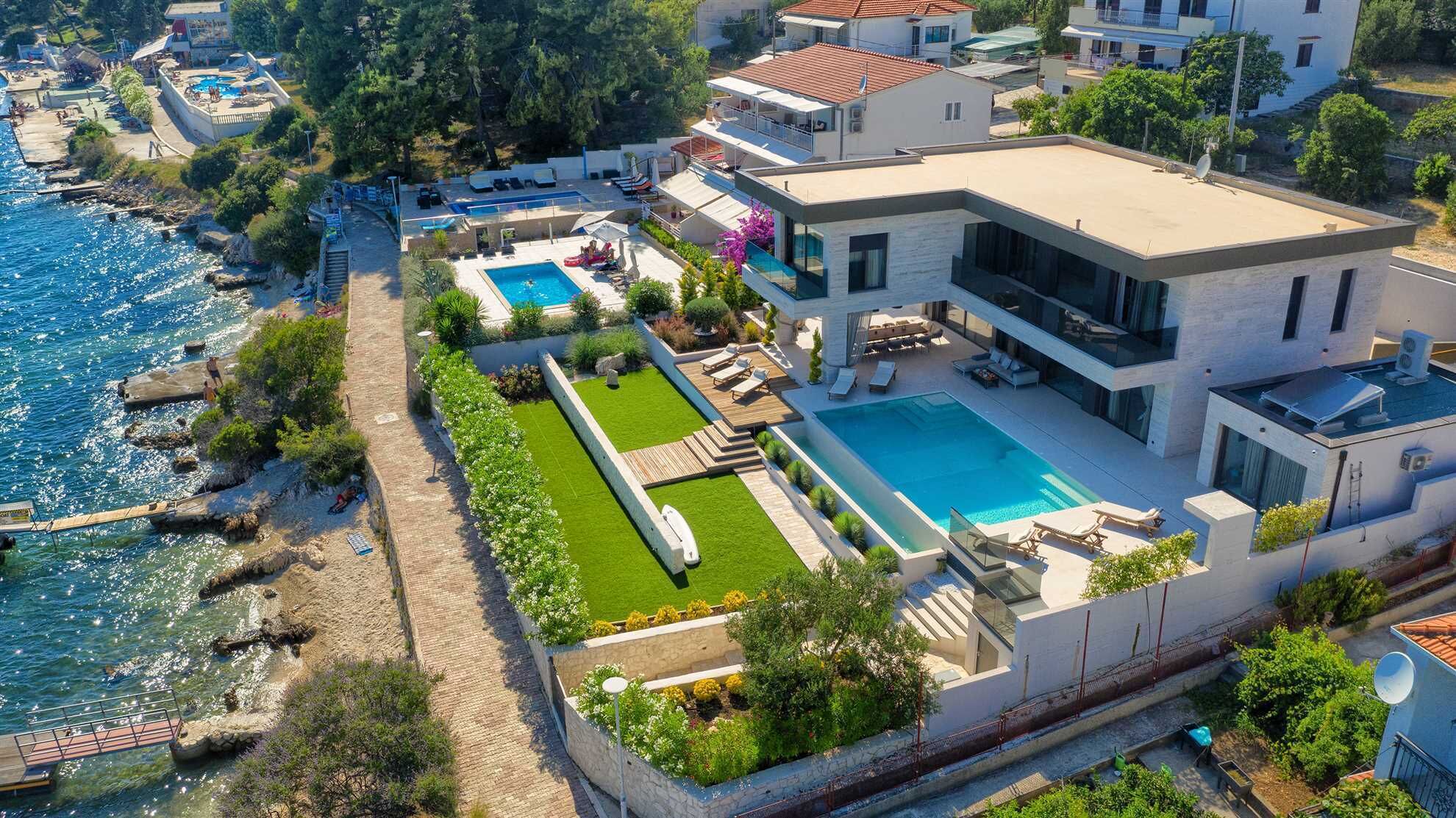 Une villa moderne dotée d’une grande piscine, d’une terrasse privée et offrant une vue sur la mer.