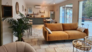 A modern living room with a sofa, a dining area, and a kitchen.