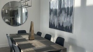 Une salle de conférence moderne, dotée d’une grande table en bois, de chaises noires, d’un grand miroir rond et d’un tableau abstrait de grande taille accroché au mur.