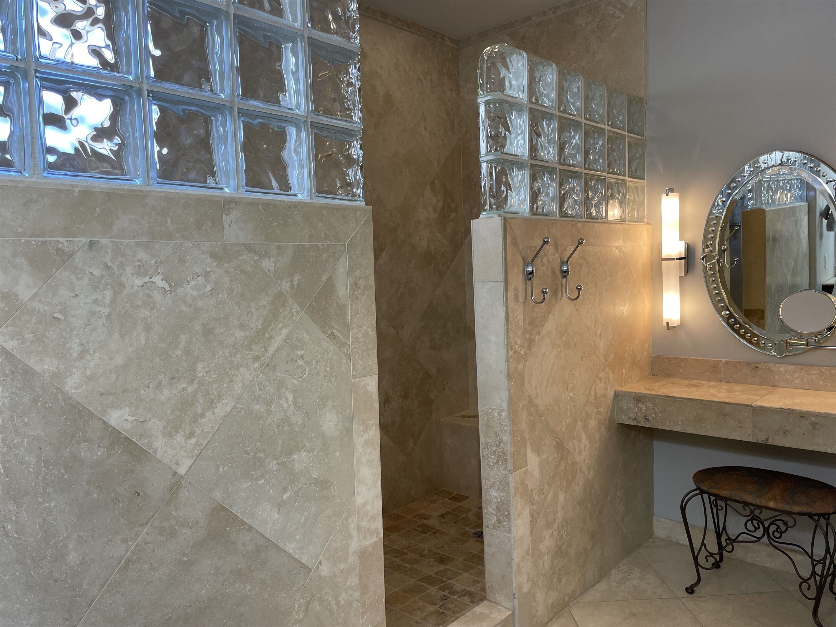 Une salle de bain comprenant un espace douche, un meuble-lavabo avec un miroir et une fenêtre avec des panneaux en verre dépoli.