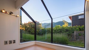 Ein Zimmer mit großem Fenster, einer Holzbank und einer Wandleuchte.