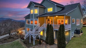 A two-story house with a covered porch, a staircase, and a view of the mountains. - 7br Asheville Mansion, Views, Pool, Full Spa, Hot Tub, Gameroom - close to DownT (Asheville)