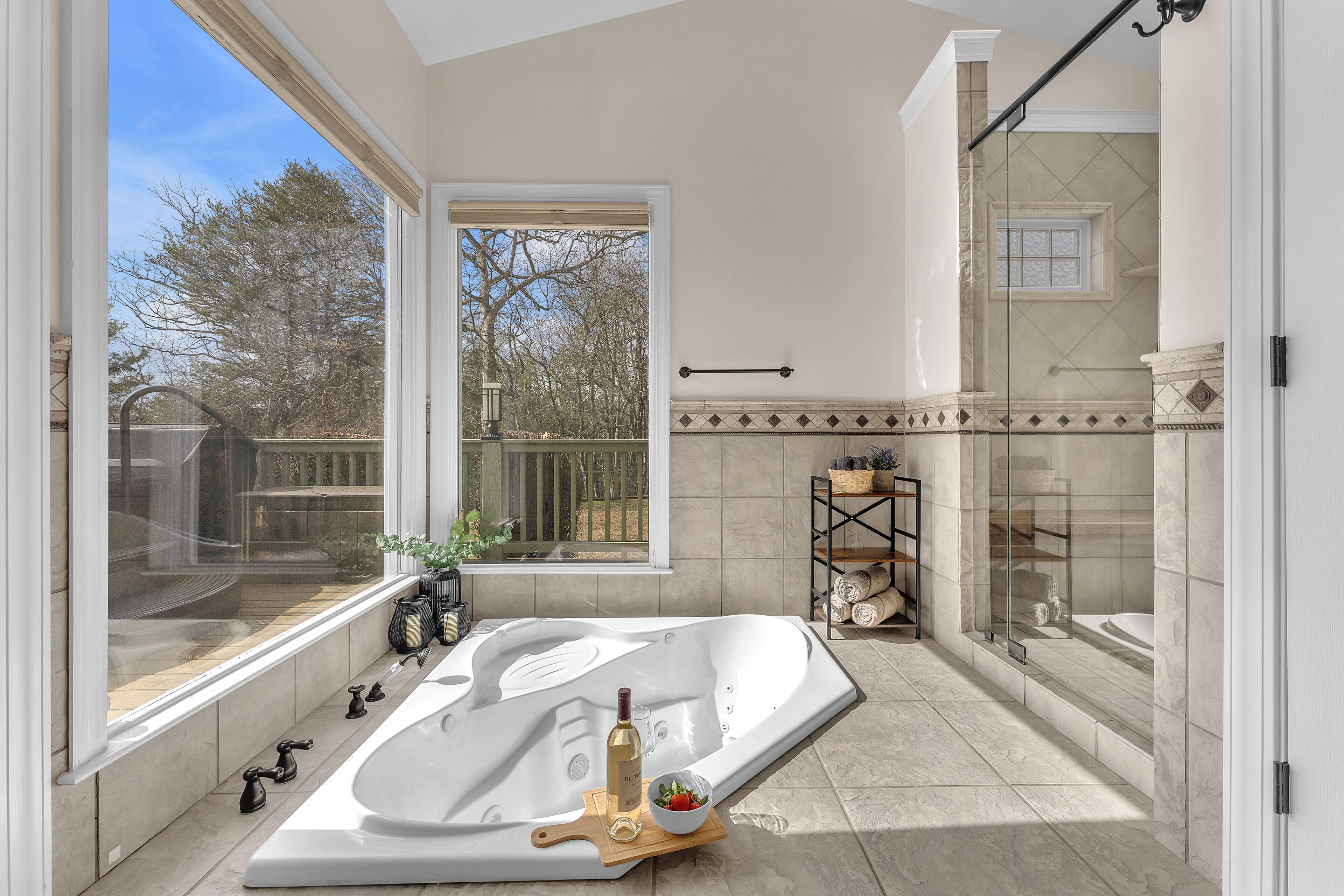 Ein modernes Badezimmer mit einer großen Badewanne, einem Fenster mit Blick auf Bäume und einer Duschkabine aus Glas.