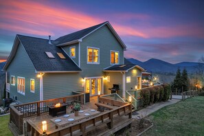 A two-story house with a deck, outdoor lighting, and a grill. - 7br Asheville Mansion, Views, Pool, Full Spa, Hot Tub, Gameroom - close to DownT (Asheville)