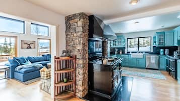 A modern kitchen with a stone accent wall, a built-in stove, and teal cabinetry.