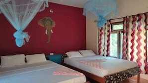 Une chambre avec deux lits, un mur rouge et une tête d’éléphant décorative.
