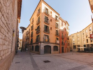 A multi-story building with balconies, a cobblestone street, and a clear sky.