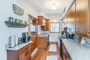 A compact kitchen with wooden cabinets, a coffee maker, and a granite countertop.