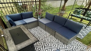 A covered patio area with a sectional sofa, a small table, and a patterned rug. - Family Retreat Near Lake Michigan | Extended Work Stay (Racine)