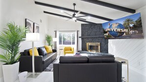 A modern living room with a black sofa, a yellow armchair, a white floor lamp, and a large painting of a globe.