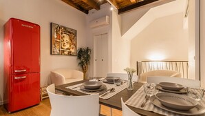 A dining area with a wooden table set for four, a red refrigerator, and a painting on the wall. - Veronetta The Cellar (Verona)