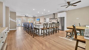 A spacious kitchen with a central island, wooden chairs, and a dining table.