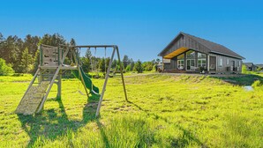 Een modern huis met een ruim terras en een schommel in een grasveld.
