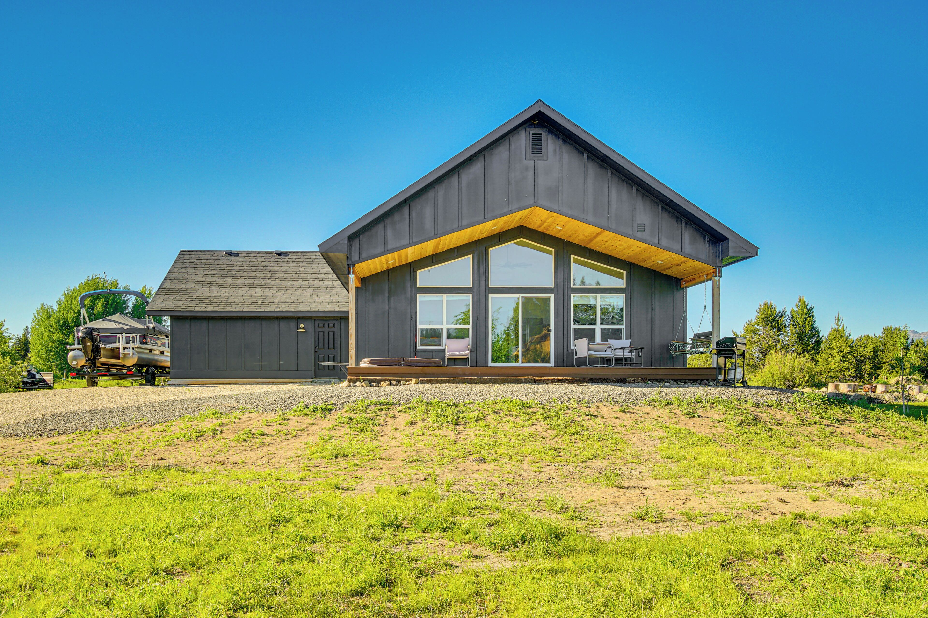 Une maison moderne dotée d’une grande véranda, d’un garage et d’une pelouse bien entretenue.