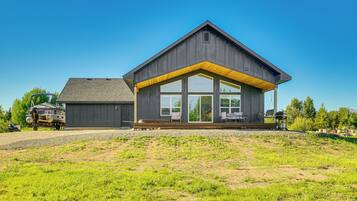Une maison moderne dotée d’une grande véranda, d’un garage et d’une pelouse bien entretenue.