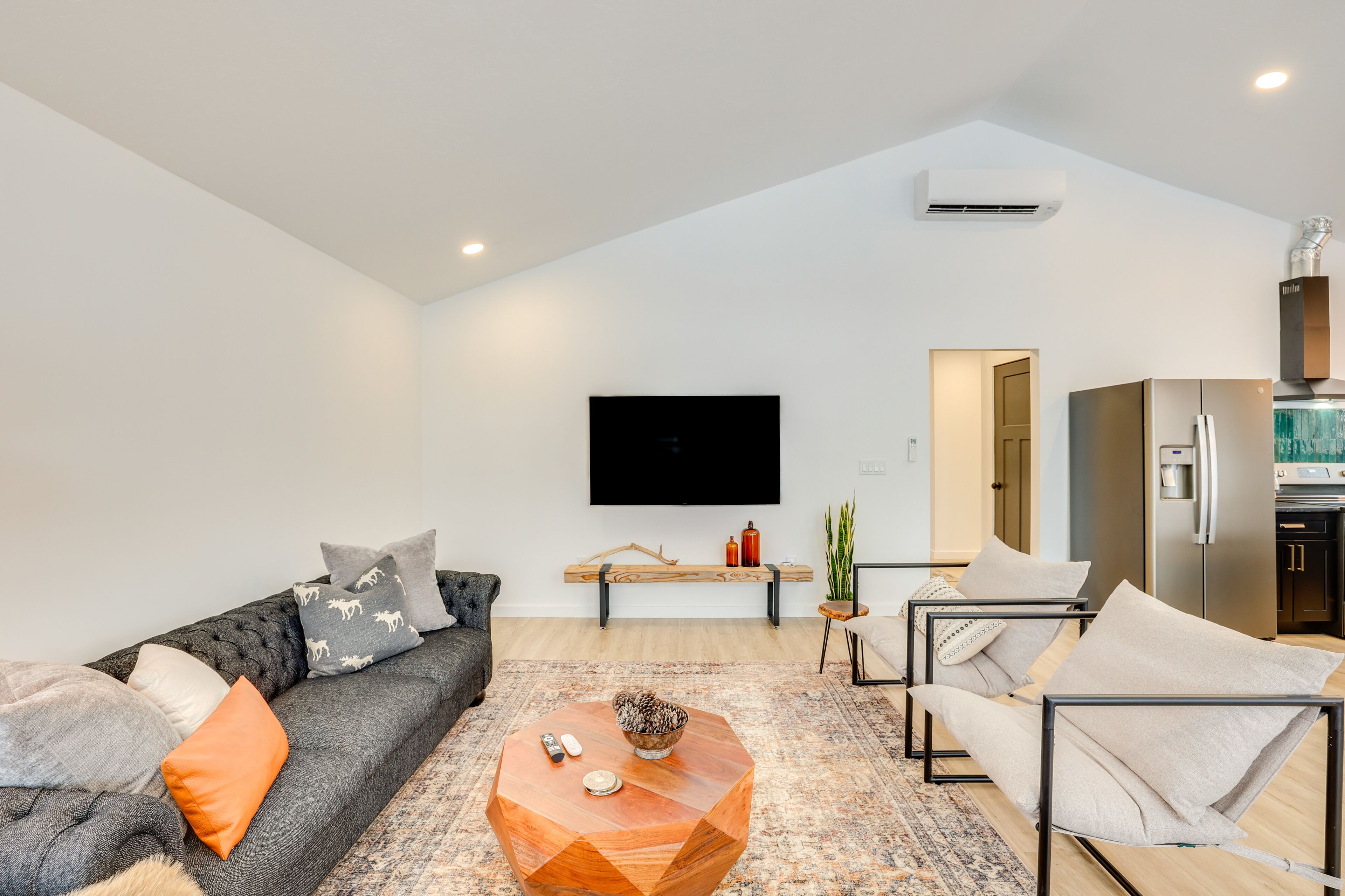 Un salon moderne avec un canapé, une table basse et un téléviseur à écran plat fixé au mur.