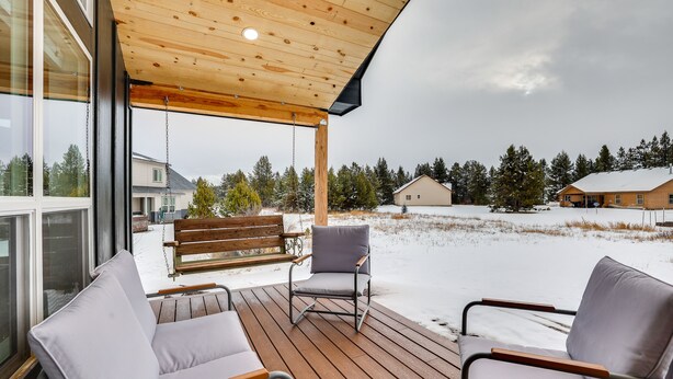 Een overdekt terras met houten vloer en twee grijze stoelen.