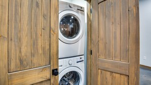 A laundry room with wooden doors and two stacked washing machines. - Serene Yantis Getaway - 1 Mi to Lake Fork! (Yantis)