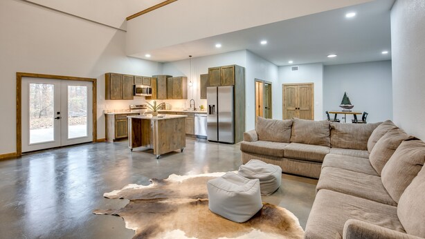 A spacious living area with a large sofa, ottomans, and a cowhide rug. - Serene Yantis Getaway - 1 Mi to Lake Fork! (Yantis)