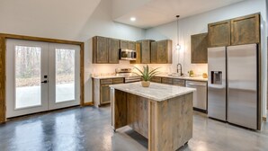 A modern kitchen with wooden cabinets, stainless steel appliances, and a large island. - Serene Yantis Getaway - 1 Mi to Lake Fork! (Yantis)
