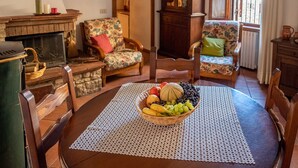 A cozy living room with a wooden table, floral armchairs, a fireplace, and a fruit basket. - AramoVerde
Tuscan house in the heart of green hills in a medieval village (Aramo)