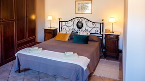 A bedroom with a double bed, two bedside tables, a wooden wardrobe, and a framed picture on the wall. - AramoVerde
Tuscan house in the heart of green hills in a medieval village (Aramo)