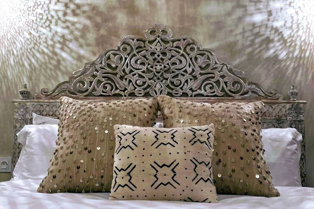 Un lit doté d’une tête de lit décorative, de deux oreillers à motifs étoilés et d’un plaid décoratif.