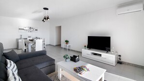 En moderne stue med sofa, sofabord, fjernsyn og spiseområde med stole og bord.